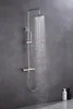 A modern stainless steel shower system with water flowing from the overhead shower head, set against a dark gray tiled wall. Produktbild-Vorschau