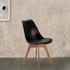 A black chair with wooden legs is shown against a textured wall and wooden floor. Anteprima dell’immagine prodotto