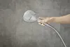 A hand holding a shower head in front of a tiled wall. Anteprima dell’immagine prodotto
