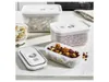 A set of three clear plastic food storage containers with white lids, filled with various snacks, arranged on a countertop. Produktbild-Vorschau