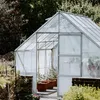 A greenhouse with plants inside, set in a garden. Produktbild-Vorschau