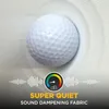 A golf ball is placed on a textured fabric surface, with sound wave graphics and a dB meter overlay indicating sound dampening. Produktbild-Vorschau