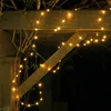 A string of fairy lights draped over wooden beams in an outdoor setting at night. Produktbild-Vorschau