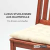 A close-up of a cream-colored chair cushion on a wooden chair. Anteprima dell’immagine prodotto