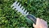 A hand holding a Bosch EasyShear Akku-Strauchschere (cordless hedge trimmer) and trimming a green hedge. Anteprima dell’immagine prodotto