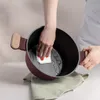 A person is cleaning the inside of a pot with a white cloth. Anteprima dell’immagine prodotto