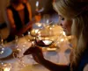 A woman is smelling a glass of red wine at a table setting. Náhled obrázku produktu