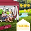 A family is enjoying themselves under a red pop-up gazebo in a grassy outdoor setting near a lake. Anteprima dell’immagine prodotto