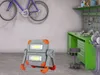 A work light is placed on the floor in a garage or workshop, with a bicycle mounted on the wall and a workbench in the background. Produktbild-Vorschau
