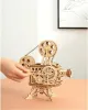 A wooden model of a film projector is shown on a table, with a hand turning a knob. Produktbild-Vorschau