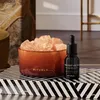 A Rituals Velvet Oudh Salzsteindiffuser with Himalayan crystals and a small bottle of diffuser oil are displayed on a black and white striped surface. Produktbild-Vorschau