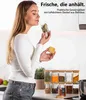 A woman is smelling a spice jar in a kitchen setting, with a set of spice jars displayed on the counter. Anteprima dell’immagine prodotto