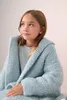 A young girl wearing a light blue knitted cardigan. Produktbild-Vorschau