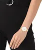 A woman's arm wearing a gold watch with a white face. Produktbild-Vorschau