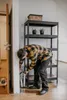 A man is using a step ladder in a room with a shelf unit. Produktbild-Vorschau
