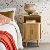 A bedside table next to a bed with pillows and a blanket. Produktbild-Vorschau