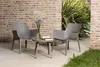 Two chairs and a table on a patio with a brick wall and plants. Produktbild-Vorschau