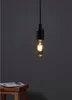 A single light bulb hangs from a black cord against a dark gray background. A wooden stool with a book on it is visible in the lower left corner. Anteprima dell’immagine prodotto
