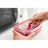A person is holding a red food container with a clear lid, about to place it in a microwave. Anteprima dell’immagine prodotto