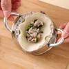 Hands using a stainless steel dumpling maker to fill it with meat and green onions. Produktbild-Vorschau