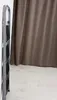 A folded metal stepladder with four steps stands against a white wall next to a brown curtain. Náhled obrázku produktu