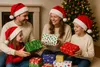 A family is exchanging Christmas gifts in front of a decorated Christmas tree. Produktbild-Vorschau