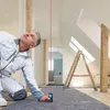 A man is using a laser distance measurer in a room under construction. Voir les images du produit