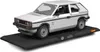 A model car of a white Volkswagen Golf GTI is displayed on a black platform with a German flag detail. Podgląd zdjęcia produktu