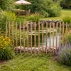 A garden scene with a pond and a wooden fence. Produktbild-Vorschau