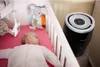 A baby sleeping in a crib next to a Philips humidifier. Produktbild-Vorschau