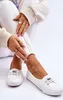 A person is sitting down, showing off their white sneakers. Voir les images du produit