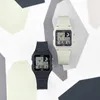 Two Casio digital watches, one black and one cream, are displayed on a white surface with geometric gray and cream shapes in the background. Náhľad obrázku produktu