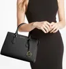 A woman is holding a black Michael Kors handbag. Produktbild-Vorschau