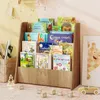 A wooden bookshelf filled with children's books, placed on a patterned rug with toys scattered around. Podgląd zdjęcia produktu