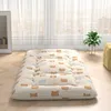 A floor mattress with a bear pattern, placed on a wooden floor in front of sheer curtains. Produktbild-Vorschau