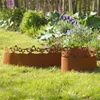 Two rusty metal garden borders with decorative cutouts are placed on a grassy lawn in front of a flower bed. Produktbild-Vorschau