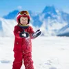 A child in ski gear is playing in the snow with mountains in the background. Náhled obrázku produktu
