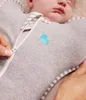 A close-up shot of a baby swaddled in a gray Love to Dream swaddle, with a hand zipping it up. Produktbild-Vorschau