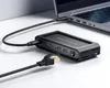 A black docking station is connected to a laptop, with an Ethernet cable plugged into the docking station. Produktbild-Vorschau