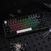A black mechanical keyboard with RGB lighting is displayed on a black textured surface, surrounded by steampunk-themed decorative elements. Produktbild-Vorschau