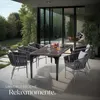 An outdoor dining set with chairs and a table on a patio, with a garden in the background. Náhled obrázku produktu