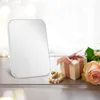 A tabletop mirror is displayed with a gift box and flowers. Podgląd zdjęcia produktu
