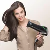 A woman is holding a hairdryer and drying her hair. Produktbild-Vorschau