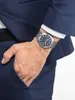 A man's hand wearing a watch is placed in the pocket of a navy blue suit. Podgląd zdjęcia produktu