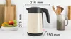A cream-colored electric kettle with dimensions shown, placed on a kitchen counter next to a fruit bowl and utensils. Anteprima dell’immagine prodotto