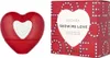 A red heart-shaped perfume bottle and its red box packaging are displayed side-by-side on a white background. Produktbild-Vorschau