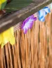 A close-up of a Hawaiian-themed party decoration, featuring a raffia skirt with colorful fabric flowers attached. Podgląd zdjęcia produktu