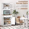 A white kitchen storage cabinet with a microwave and various kitchen items is shown in a room setting with a dining table and chairs. Podgląd zdjęcia produktu