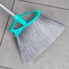 A close-up view of a broom head and part of its handle resting on a tiled floor. Voir les images du produit