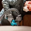 A person is using a cordless mini circular saw with a vacuum attachment. Produktbild-Vorschau